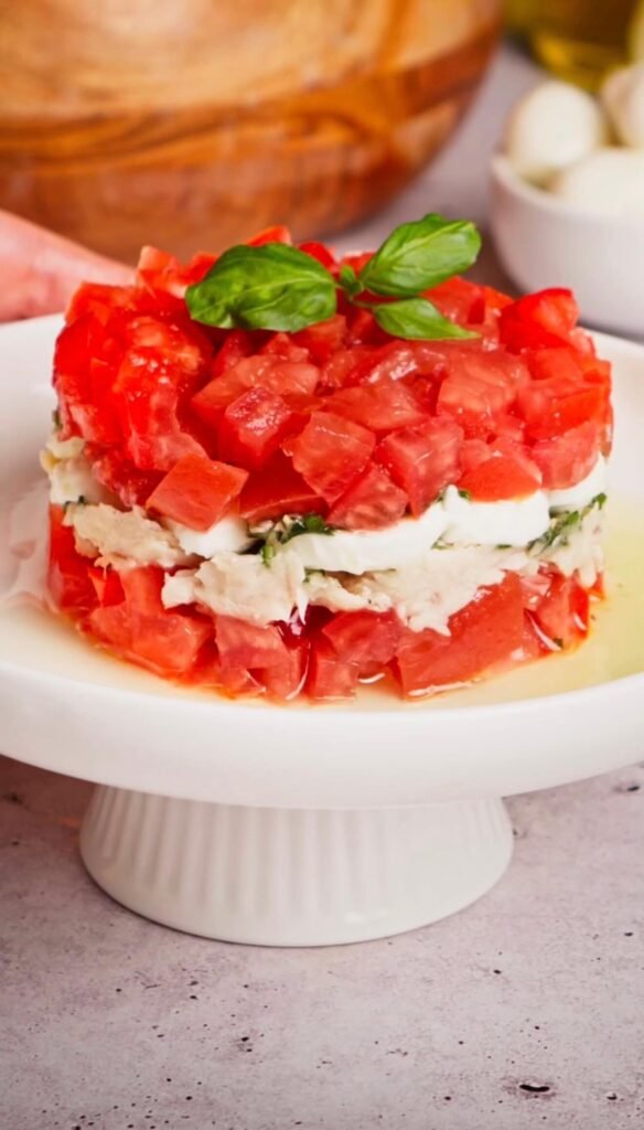 Layered Italian tuna tomato mozzarella salad with fresh basil oil served as an elegant appetizer