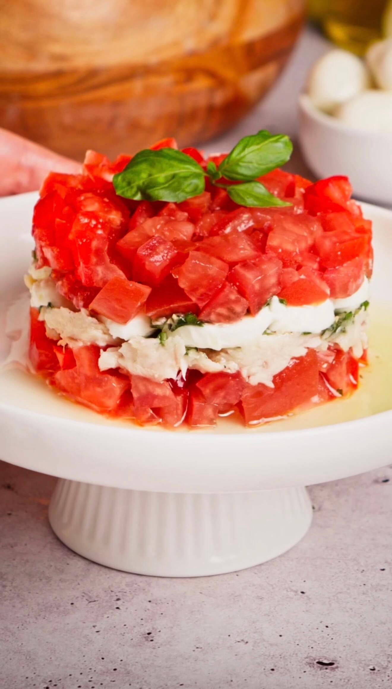 Layered Italian tuna tomato mozzarella salad with fresh basil oil served as an elegant appetizer
