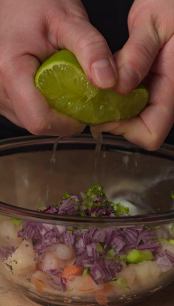 Fresh lime juice being squeezed into shrimp mixture for shrimp avocado appetizer