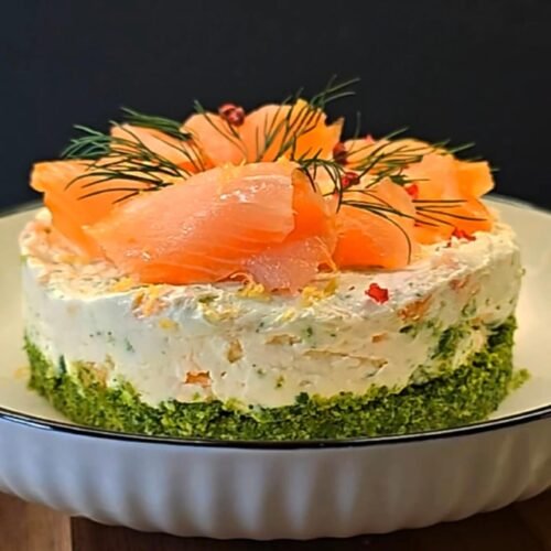 Smoked salmon cheesecake with arugula crust, topped with dill, lemon zest, and pink peppercorns