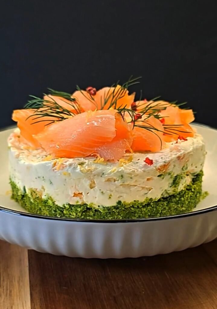 Smoked salmon cheesecake with arugula crust, topped with dill, lemon zest, and pink peppercorns
