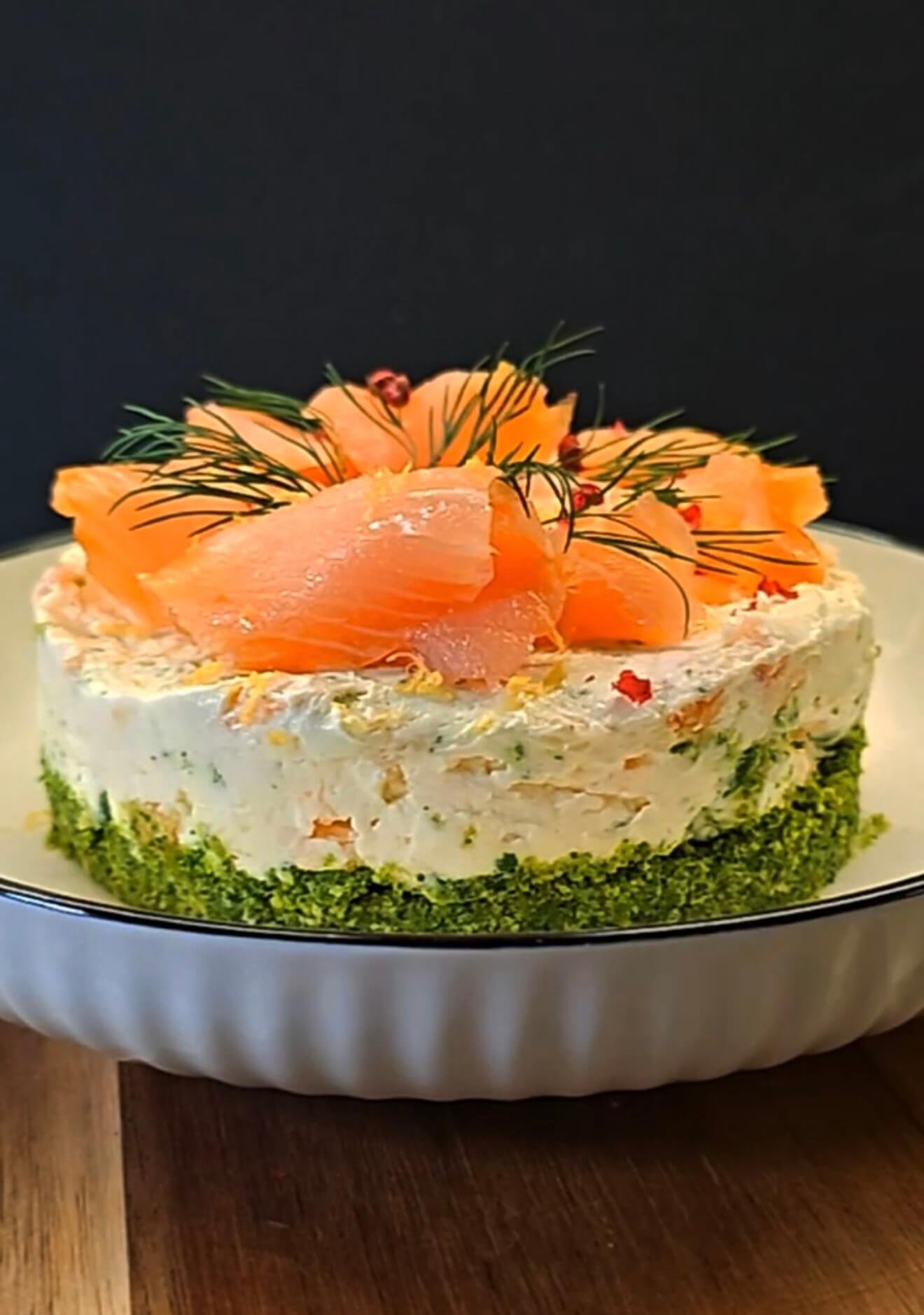 Smoked salmon cheesecake with arugula crust, topped with dill, lemon zest, and pink peppercorns