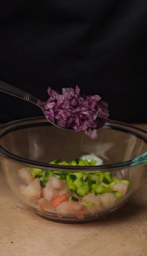 Adding finely chopped red onion to shrimp mixture for shrimp avocado appetizer