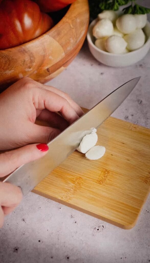 Slicing mozzarella ciliegine for an Italian tuna tomato mozzarella salad