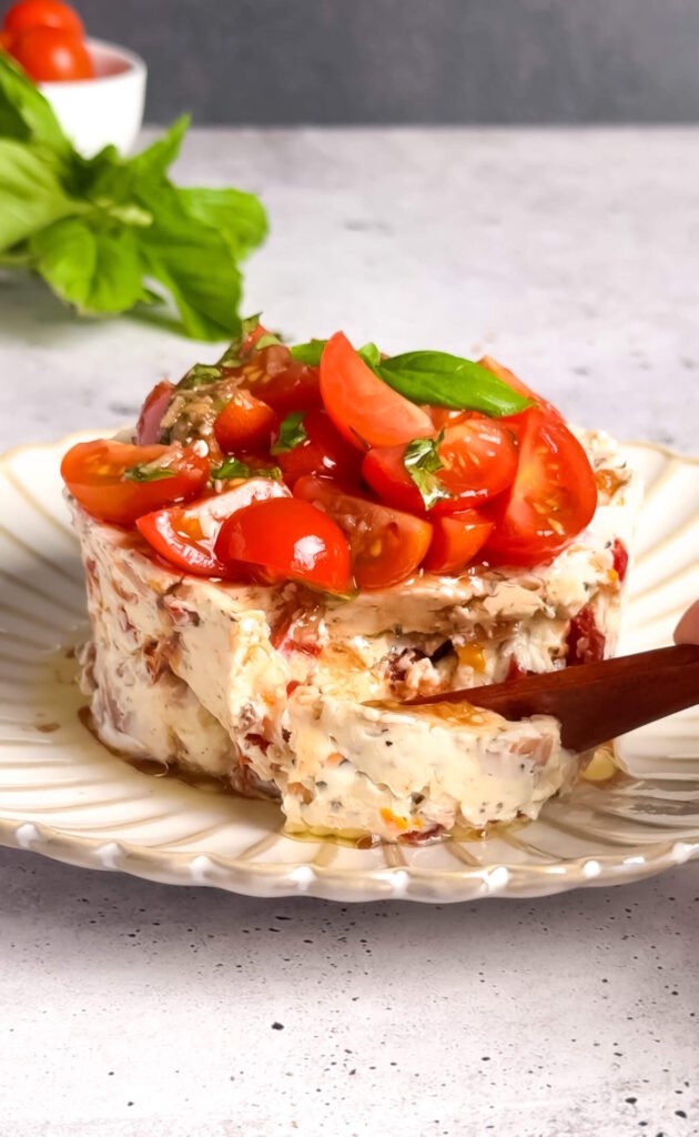 Creamy savory bruschetta cheesecake dip topped with fresh tomato bruschetta and basil