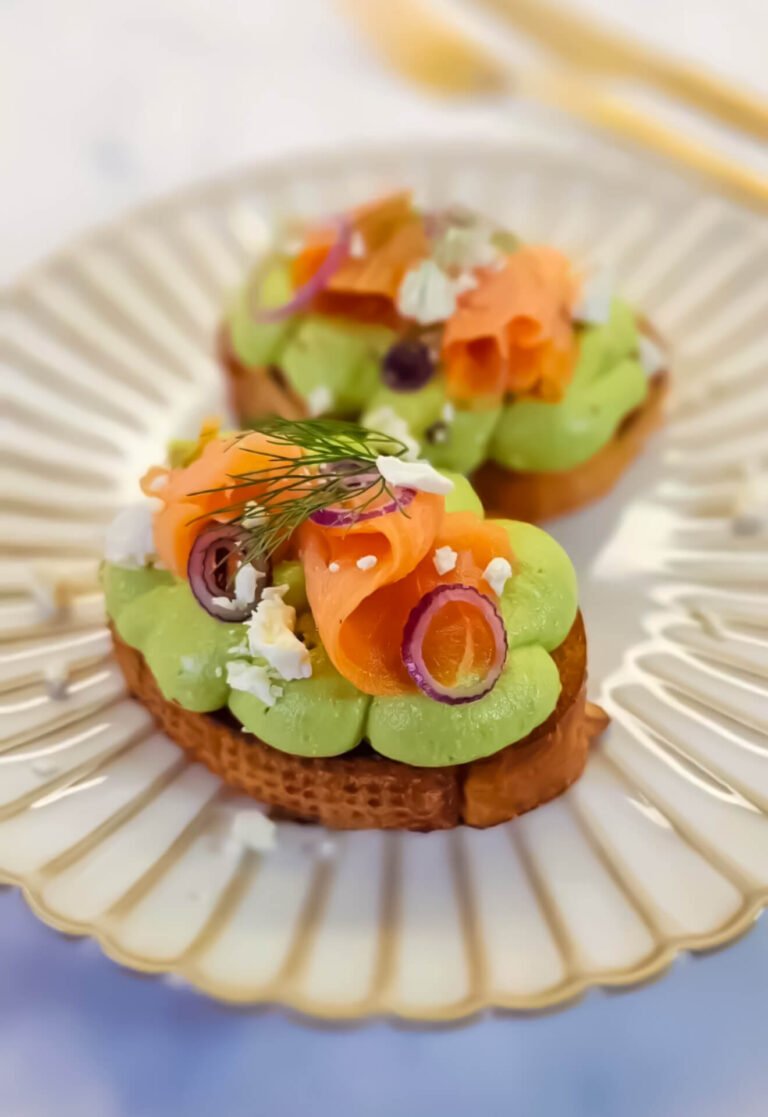 Creamy whipped avocado toast with smoked salmon, feta, and dill served on a decorative plate