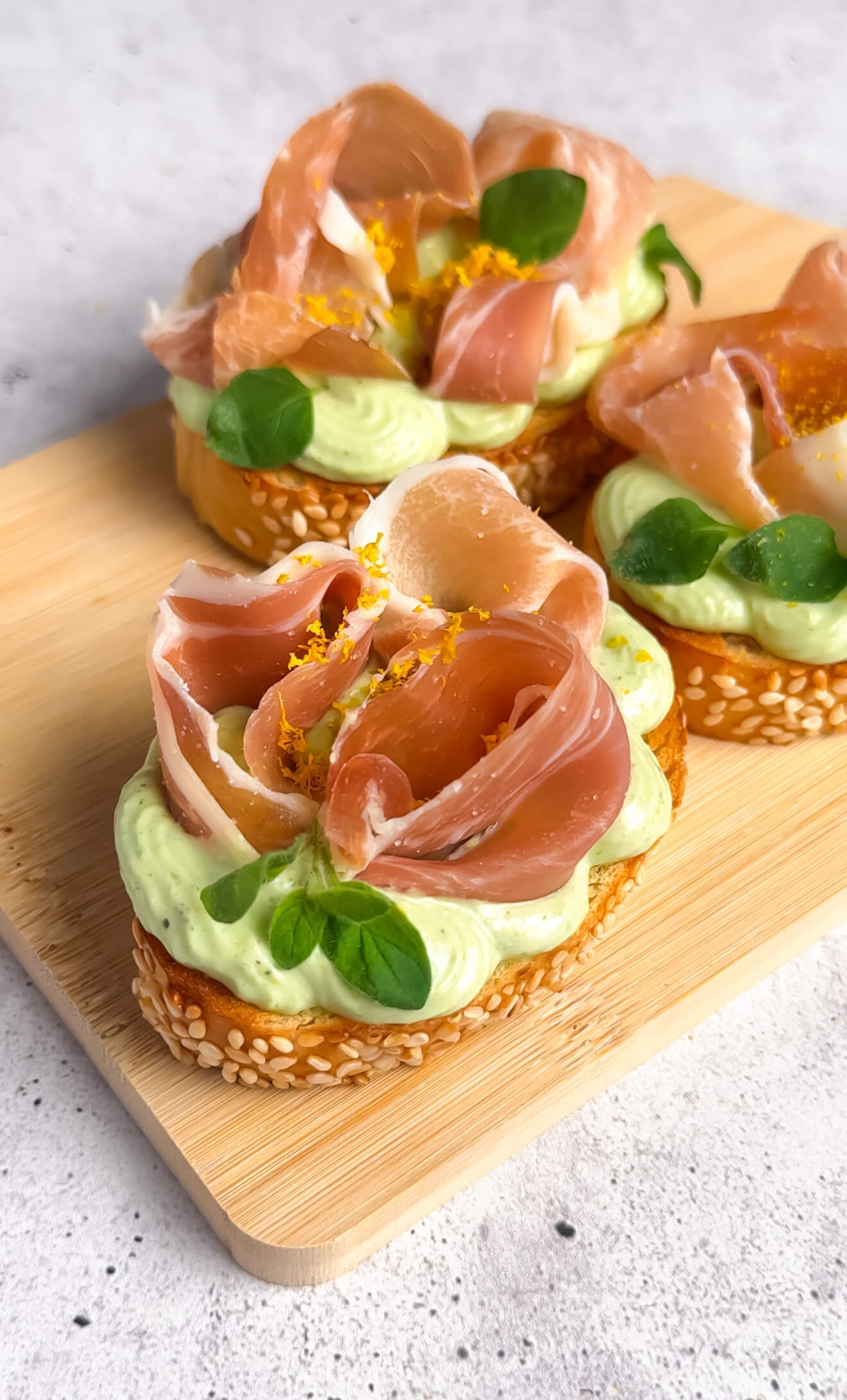 Prosciutto crostini with basil whipped ricotta arranged on wooden board