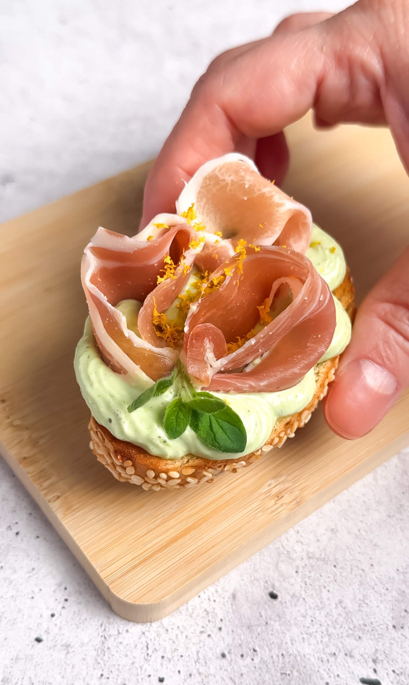 Crostini with whipped ricotta and prosciutto topped with lemon zest and basil