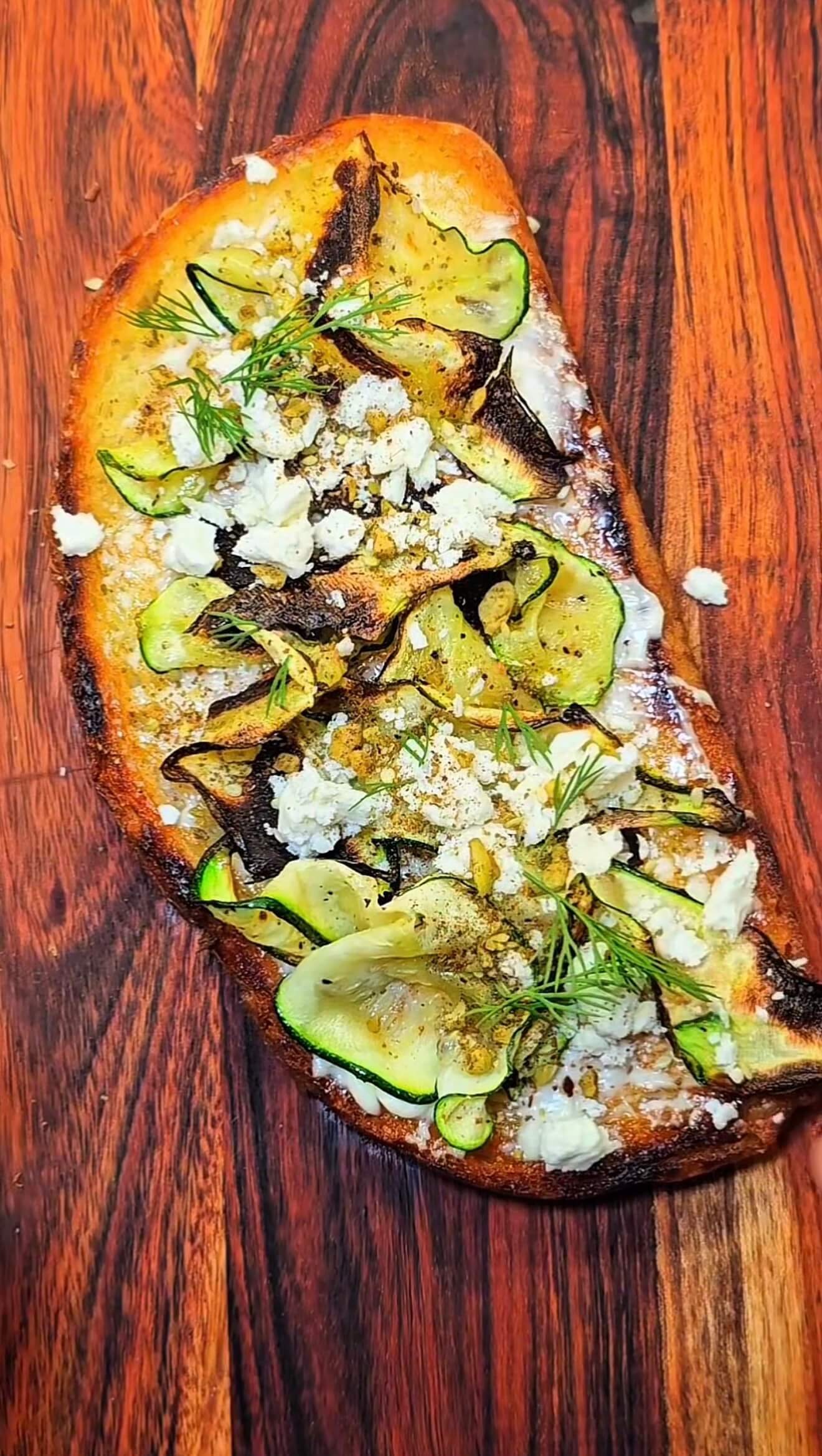Close-up of savory zucchini toast with feta and dill, showing golden toasted sourdough and lightly charred zucchini slices