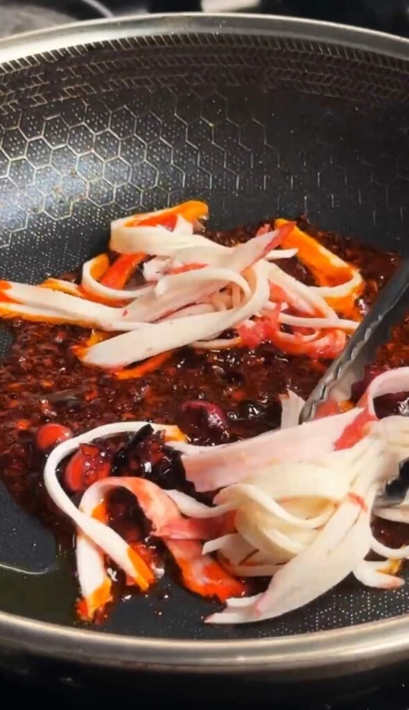 Pulled crab sticks cooking in chili crisp oil before adding the egg