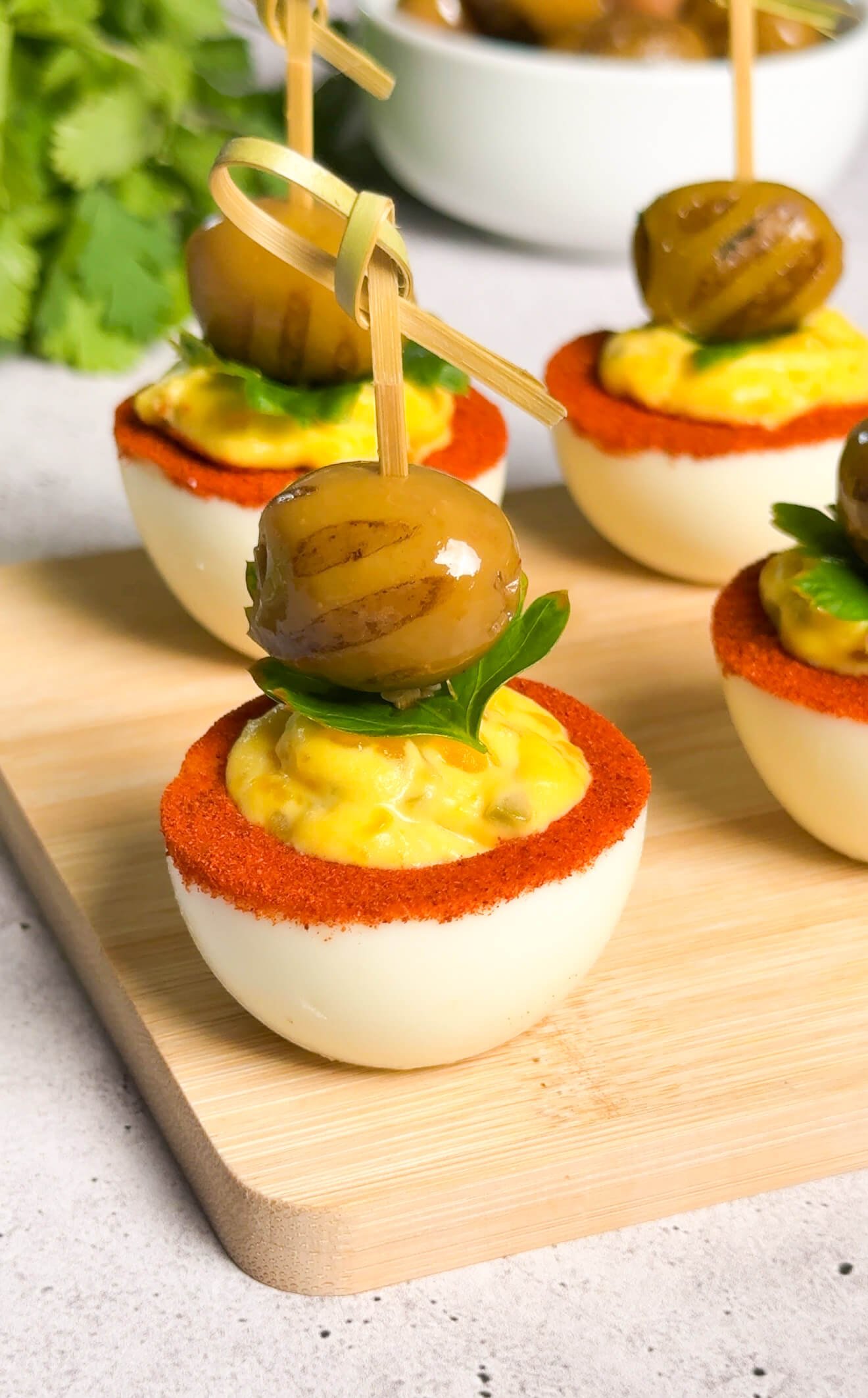 Plated dirty martini deviled eggs with paprika rim and olive garnish ready for serving