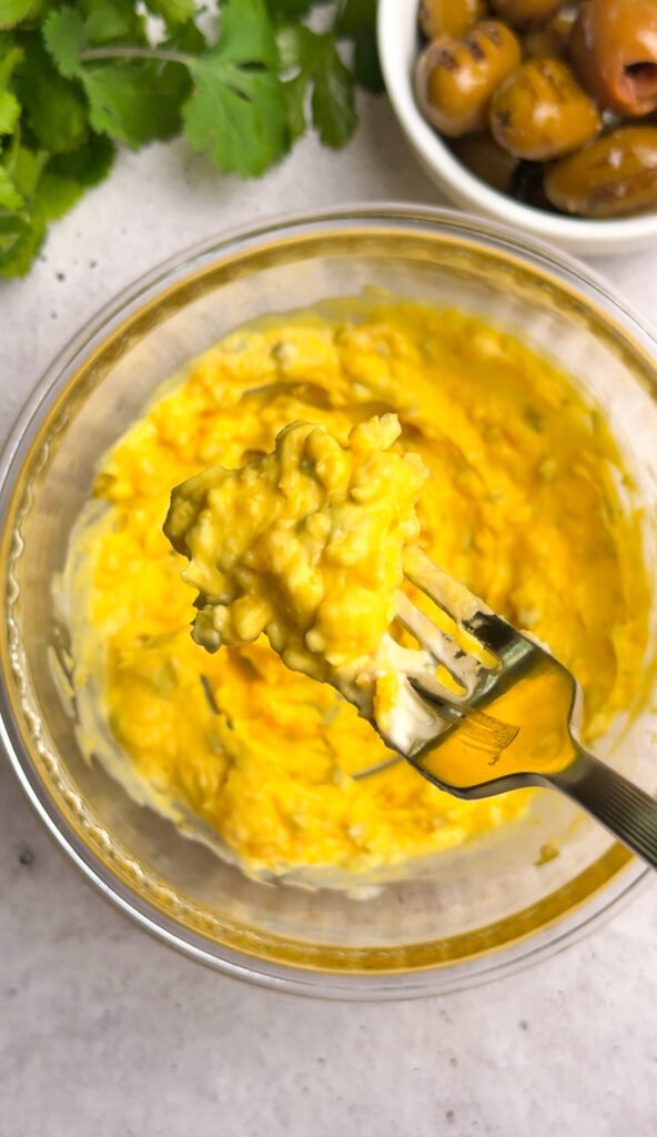 Creamy dirty martini deviled egg filling mixed with chopped green olives and mayonnaise