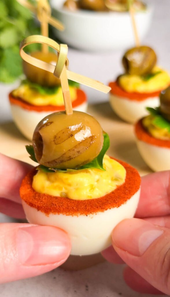 Close-up of dirty martini deviled egg showing creamy olive filling and cocktail-style garnish