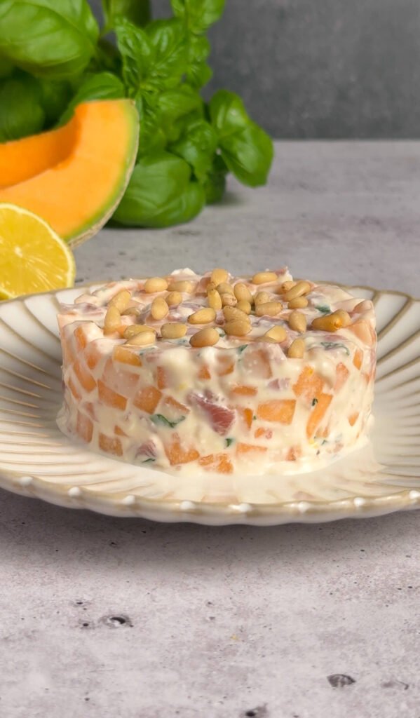 Elegant melon prosciutto tartare with mascarpone cream topped with roasted pine nuts on a decorative plate