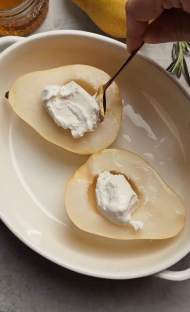 Goat cheese being added to pear halves before baking for an easy pear appetizer recipe