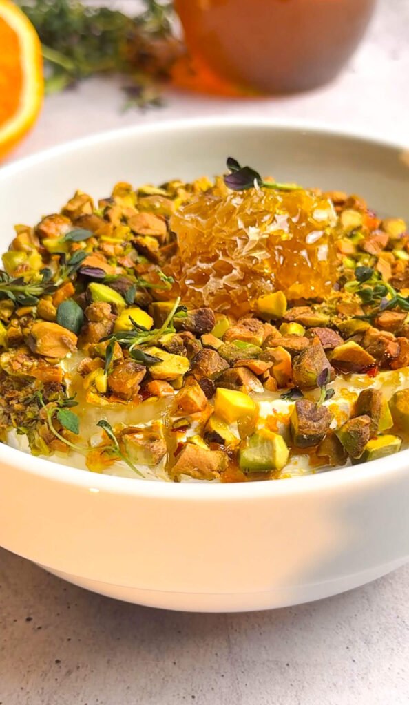 Close-up of honeycomb topping on pistachio baked brie with caramelized honey glaze and toasted nuts.