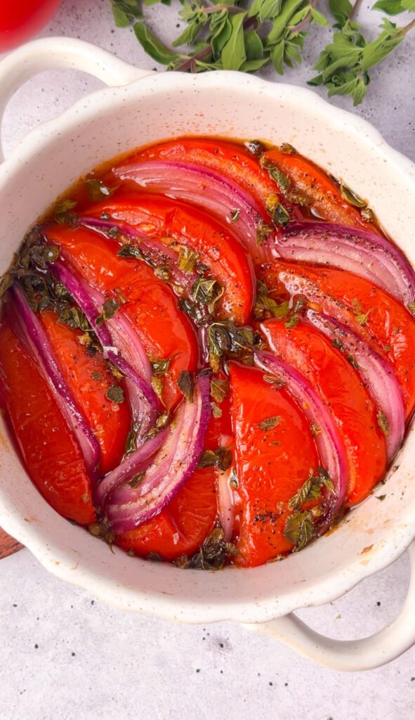 Slow-roasted tomatoes and red onion with olive oil, honey, and oregano in a baking dish