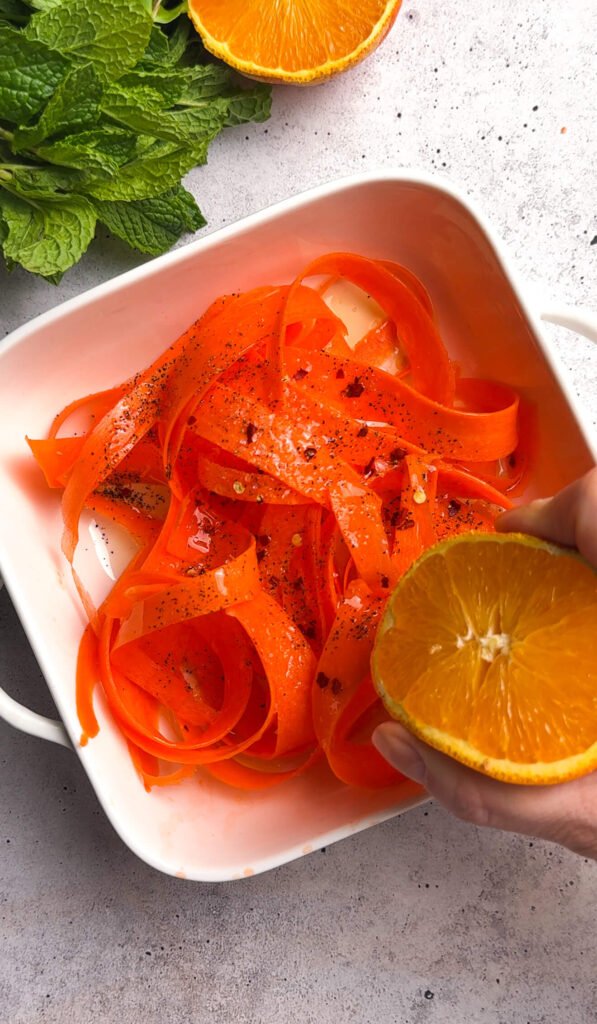 Fresh carrot ribbons seasoned with olive oil, orange juice, honey, and spices for roasted carrot burrata salad