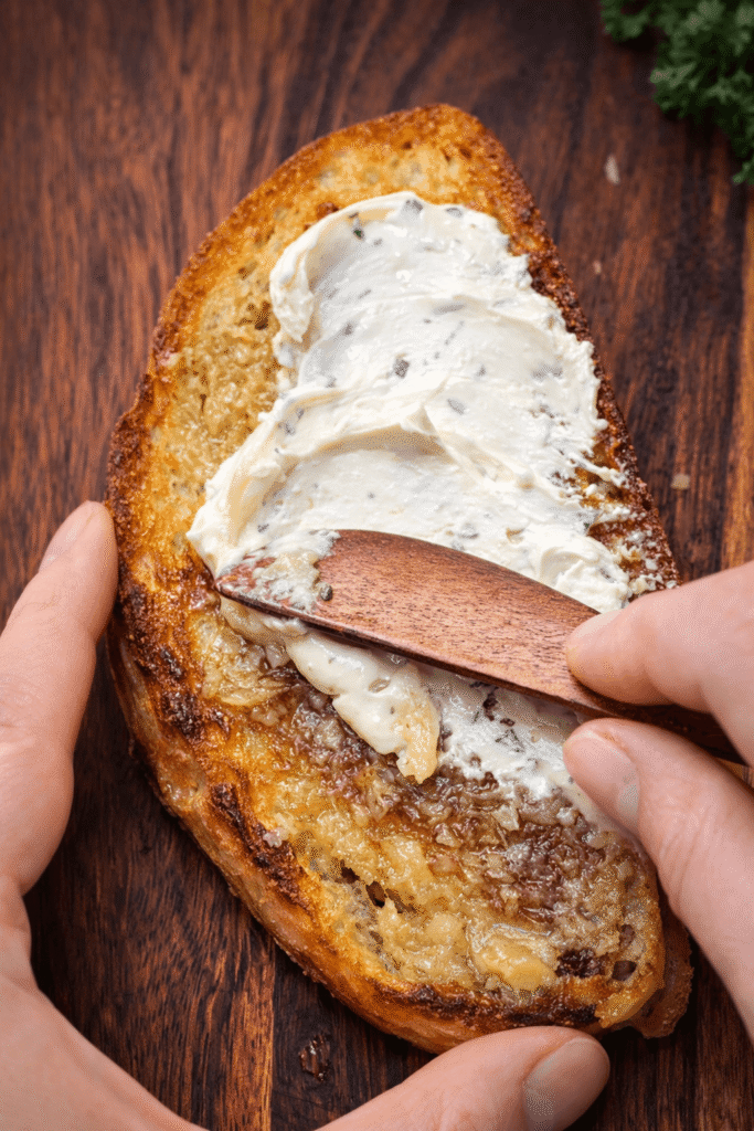 Cream cheese and mashed garlic confit spread on crispy toast for gourmet savory breakfast recipe