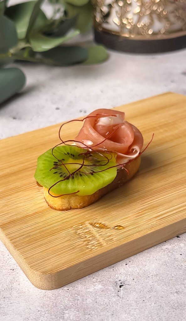 Kiwi prosciutto crostini with cream cheese and chili threads on toasted garlic baguette
