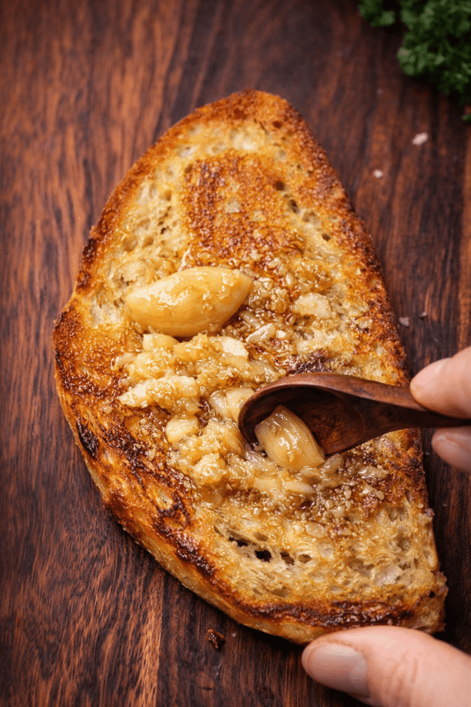 Golden toasted sourdough bread topped with soft garlic confit cloves for savory breakfast toast base