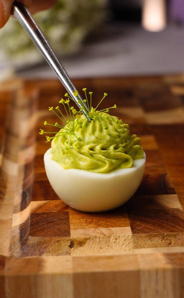 garnishing green goddess deviled eggs with delicate dill blossoms for elegant presentation
