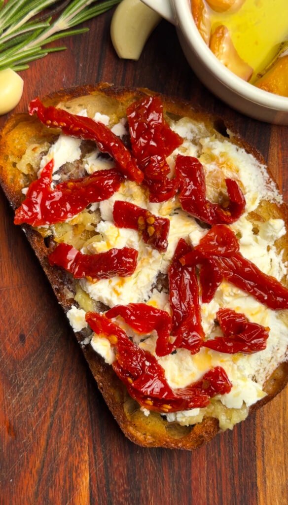 Sourdough toast topped with garlic confit, creamy goat cheese, and sun-dried tomatoes