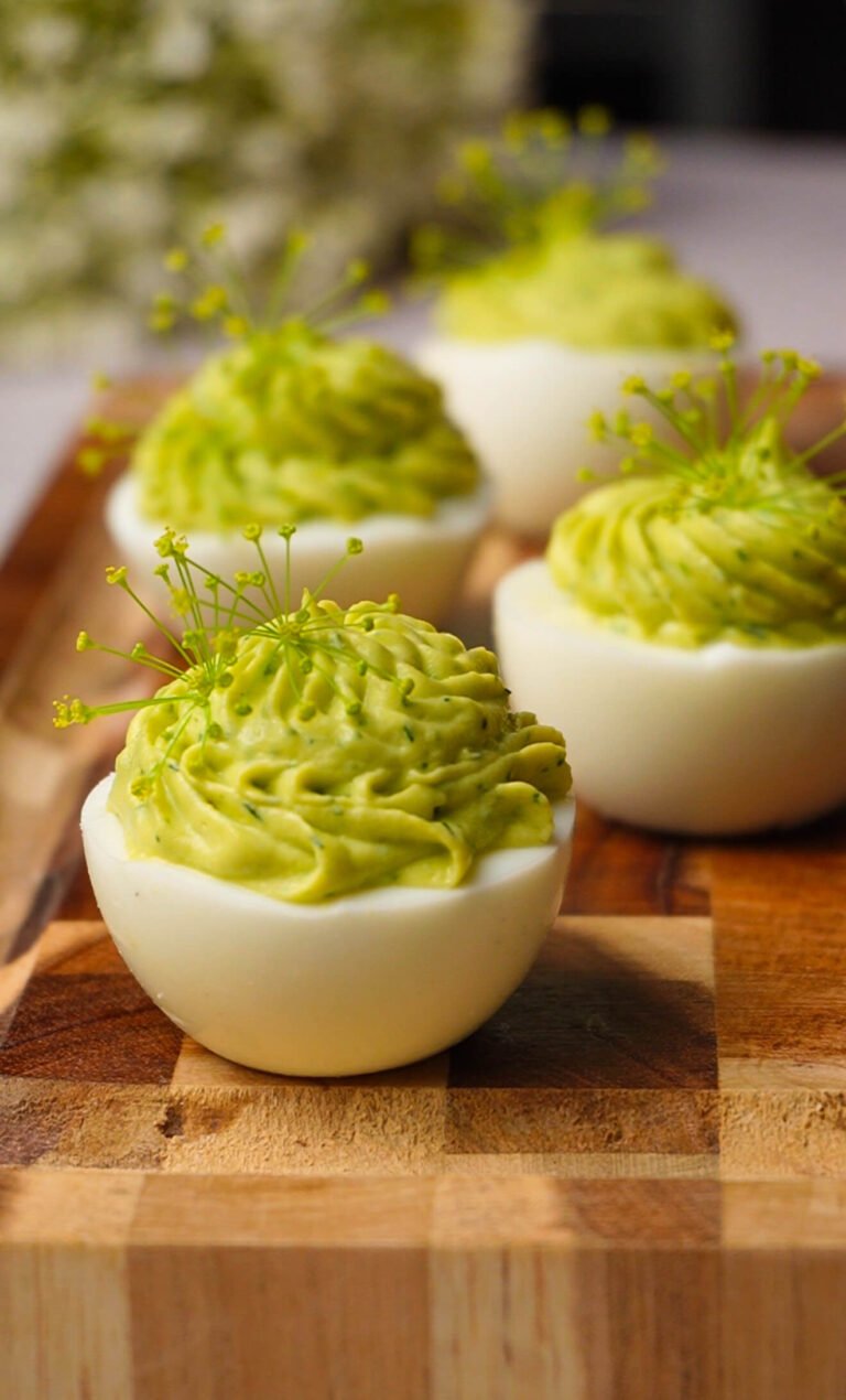 green goddess deviled eggs with avocado herb filling piped in swirl and topped with dill blossoms