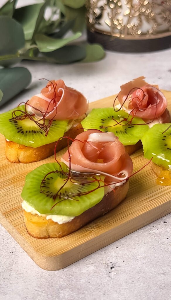 Kiwi prosciutto crostini appetizer with honey drizzle and chili threads on toasted baguette slices