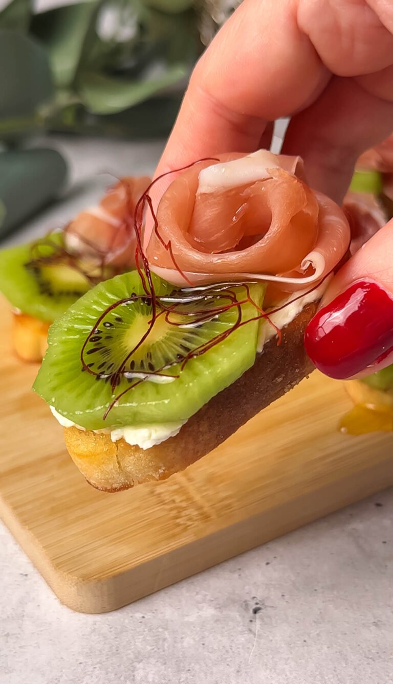 Close-up kiwi prosciutto crostini with cream cheese and honey on crispy toasted baguette