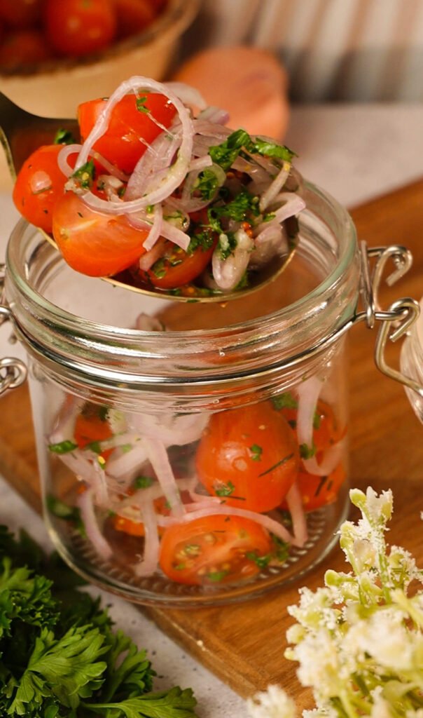 10 minute marinated cherry tomatoes with garlic herbs and onion being served from jar