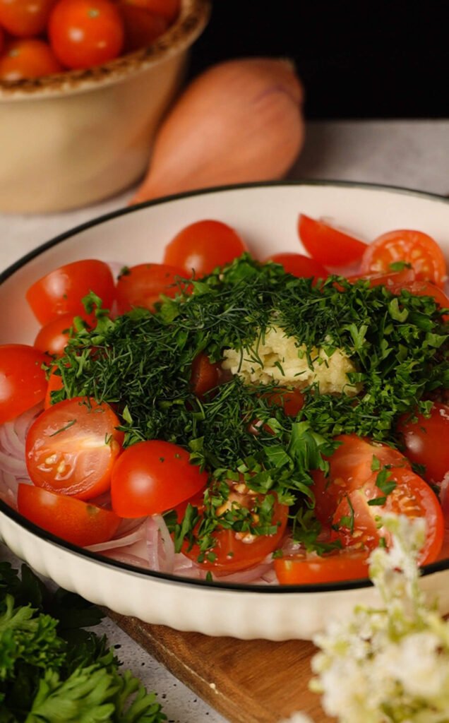 ingredients for quick marinated cherry tomatoes including fresh herbs garlic and halved tomatoes