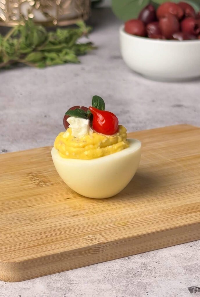 Mediterranean deviled egg topped with olive feta oregano and pepper drop garnish