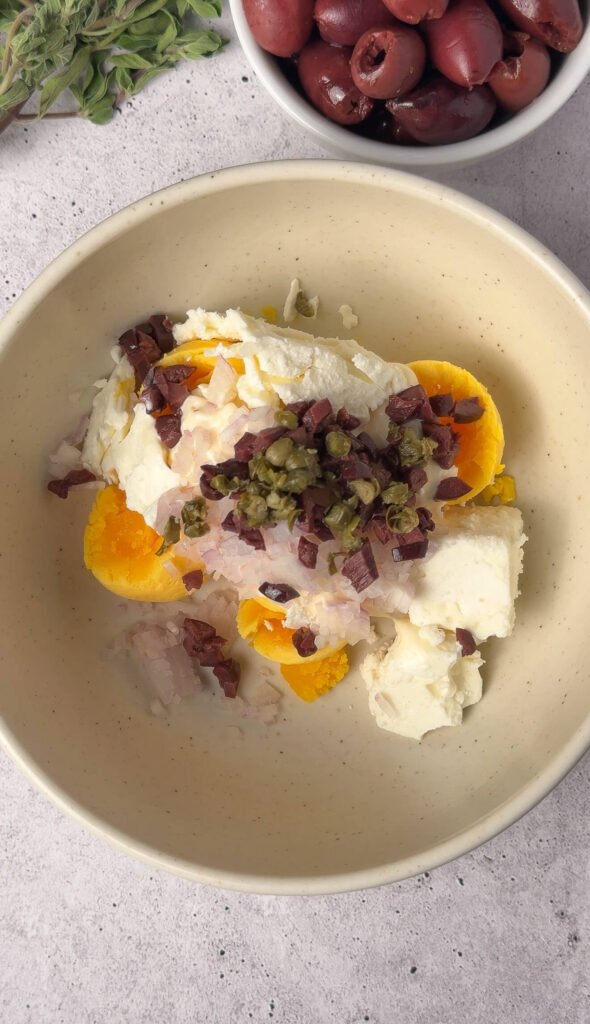 Egg yolks mixed with feta cheese, Kalamata olives, capers and onion for Mediterranean deviled egg filling