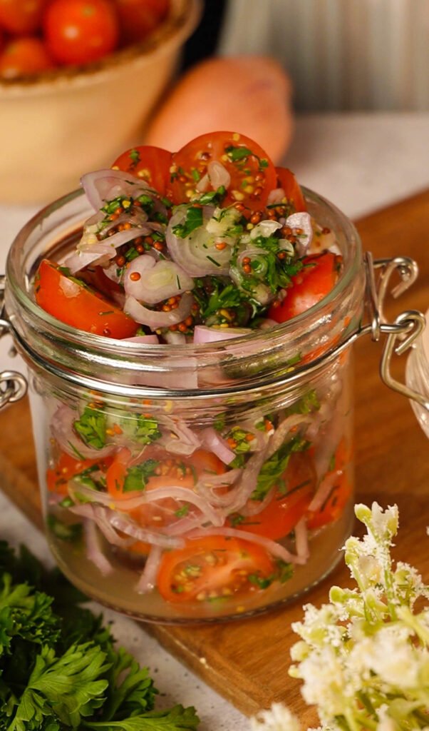 easy marinated cherry tomatoes recipe in jar with dill parsley and sliced onion