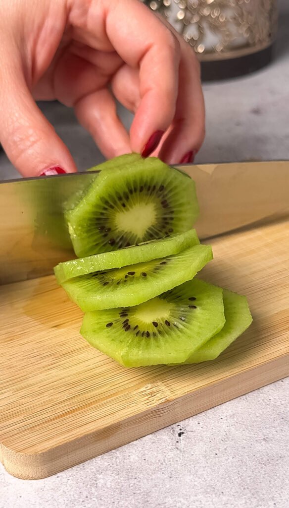 Slicing fresh kiwi for kiwi prosciutto crostini appetizer recipe
