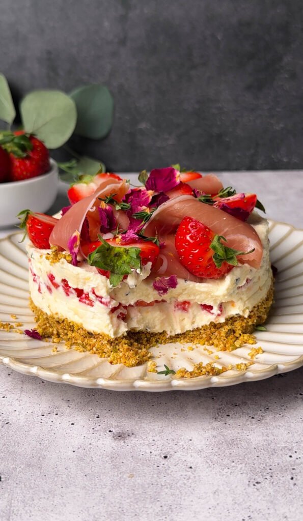 Slice of strawberry prosciutto cheesecake dip showing creamy ricotta filling layered with fresh strawberries over a pistachio cracker crust.