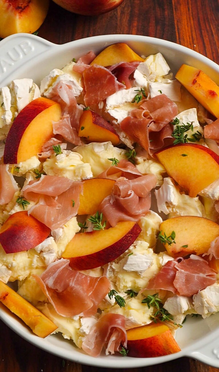 Baked brie with peach, prosciutto and thyme in a white dish ready to serve