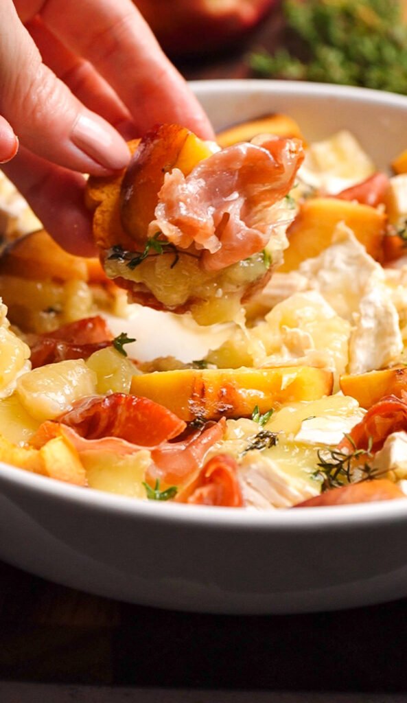 Melty baked brie with peach and prosciutto served on a crispy toast bite