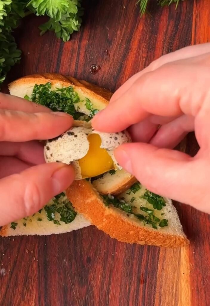 Cracking a quail egg into the center of garlic butter toast shaped like a windmill on a wooden board