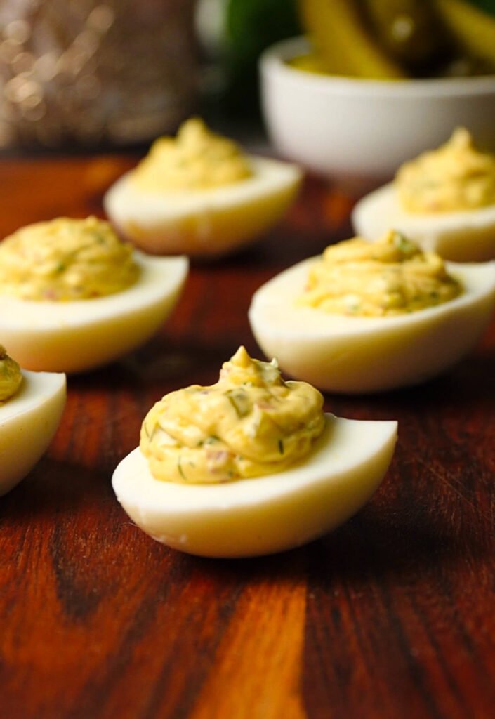 pickle deviled eggs filled and piped into egg whites on wooden board