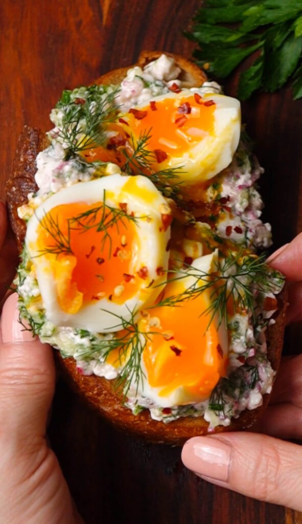 Close-up of jammy egg toast with soft yolk and fresh herbs on sourdough