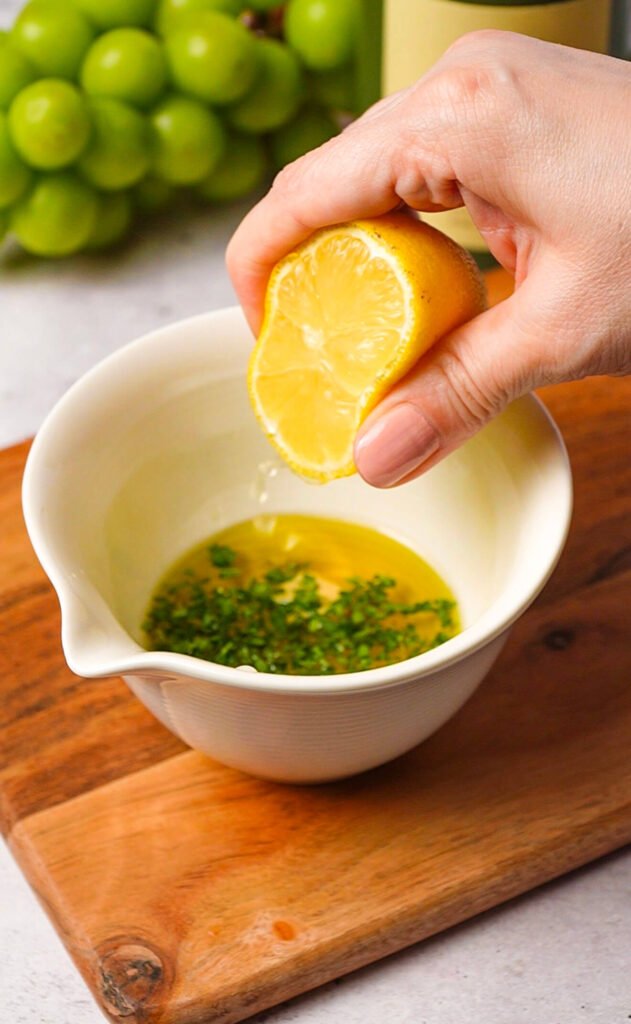 lemon juice being squeezed into olive oil dressing for waldorf salad with burrata