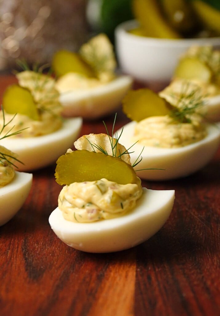 loaded pickle deviled eggs with dill pickle slices fresh dill and potato chips on top