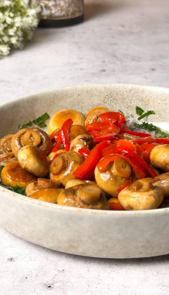 marinated mushroom salad served in bowl with sautéed mushrooms and sliced bell peppers
