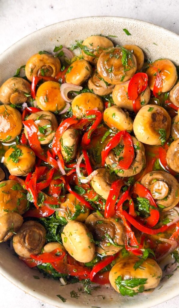 close up of marinated mushrooms with herbs and peppers glossy olive oil dressing