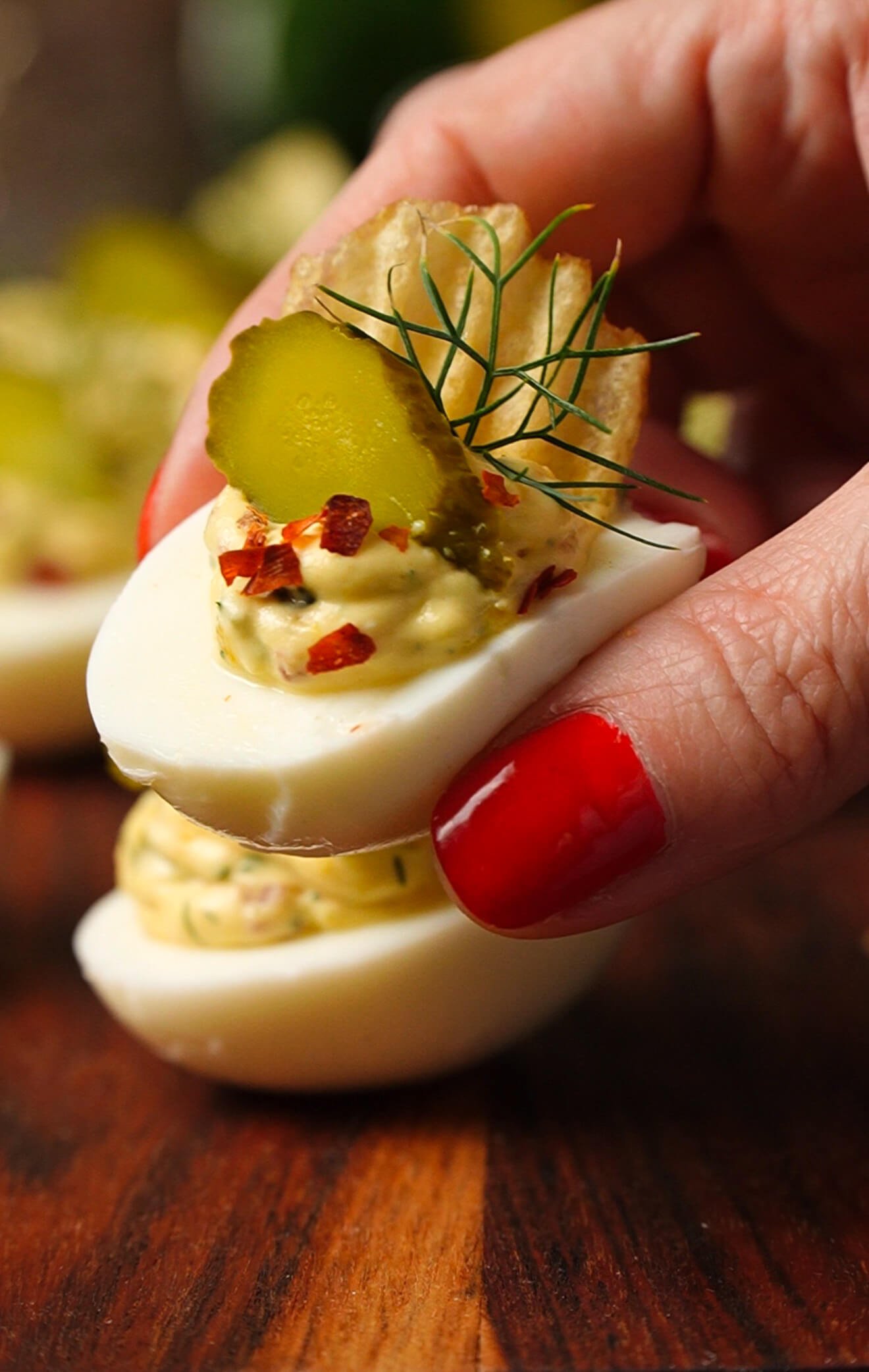 close up of pickle deviled egg with crunchy potato chip and dill garnish