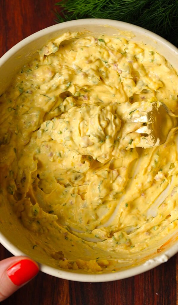 creamy pickle deviled egg filling mixed with herbs bacon and dill pickles
