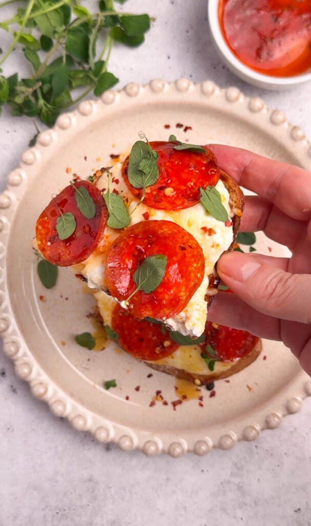 bite of pizza toast showing melted mozzarella cottage cheese and crispy sourdough texture