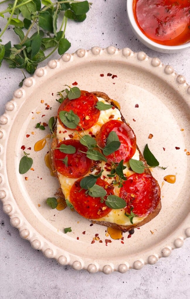 pizza toast finished with red pepper flakes hot honey and fresh oregano